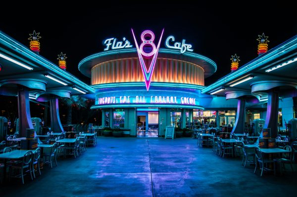 Illuminated retro diner facade at night with neon lights and empty seating.